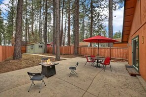 A backyard with a fire pit, outdoor table, chairs, and a red umbrella. - Mountain Bearadise (Big Bear Lake)