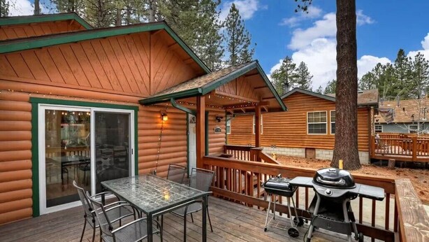 A log cabin with a deck, a glass table, chairs, and a grill. - Mountain Bearadise (Big Bear Lake)