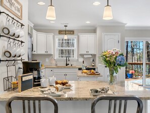 A modern kitchen with white cabinets, a coffee bar, a sign reading 'LAKE HOUSE,' and a large window overlooking a pool. - Lake Hartwell Retreat with Dock and Fire Pit (Anderson)