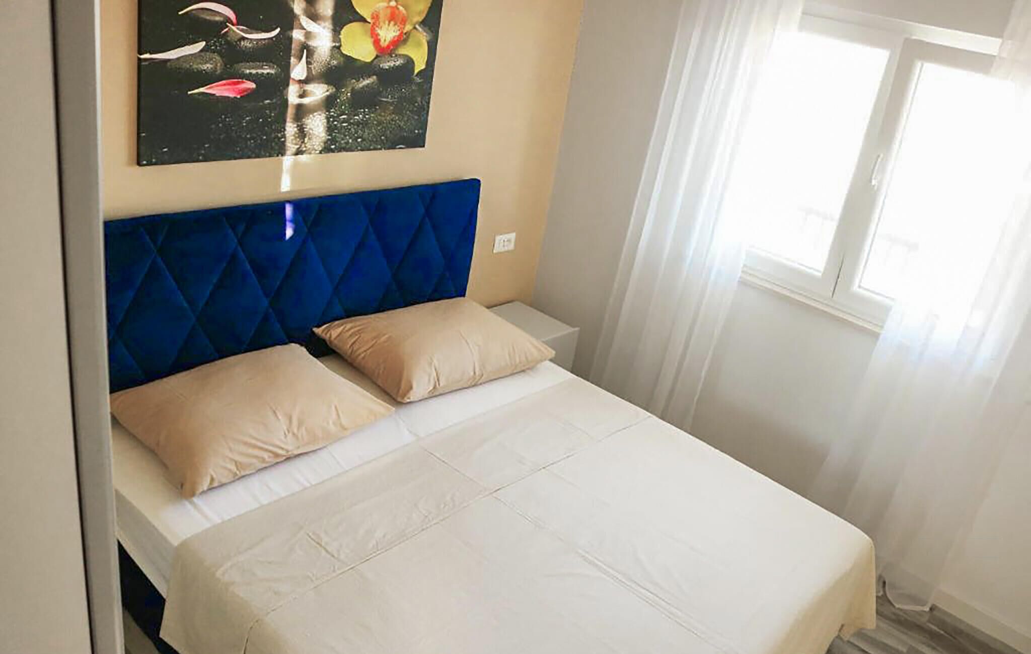 A bed with a blue headboard, two beige pillows, and a white bedspread.