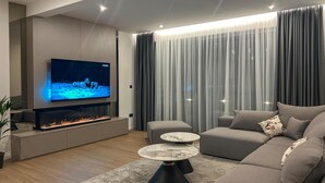 Ein modernes Wohnzimmer mit Flachbildfernseher, Kamin, Sofa und Couchtisch.