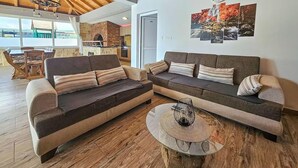 Ein Wohnzimmer mit einem Ecksofa, einem runden Glastisch und einem Kamin.
