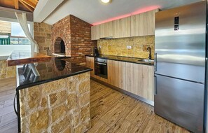 Een keuken met een bakoven, houten kasten, een roestvrijstalen koelkast en een stenen kookeiland.