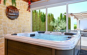Een hottub met een achtergrond van een stenen muur en uitzicht op bomen.