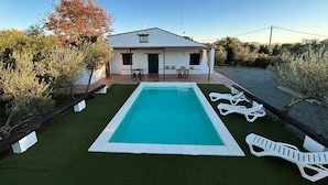 Una casa con piscina, mobiliario de jardín y un jardín.