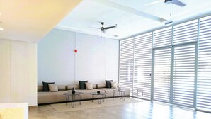 Een moderne woonkamer met een bank, twee salontafels en een plafondventilator.