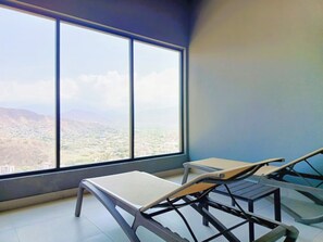 A room with a large window, two lounge chairs, and a small table. - Luxury Ocean View Apartment in Rodadero (El Rodadero)
