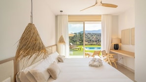 A hotel room with a bed, a desk, a chair, a lamp, and a view of a pool and landscape. - Casa Fergo Antequera by Ruralidays (Málaga)