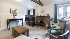 Olohuone, jossa on takka, televisio, puinen penkki ja ikkuna, jossa on verhot.