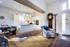 A spacious kitchen with wooden beams, a dining area with a table set for four, and a large clock on the wall. - Beautiful Coach House in the Heart of Montpellier (Cheltenham)