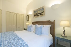 A bedroom with a bed, bedside lamps, a nightstand, a dresser, and a door.