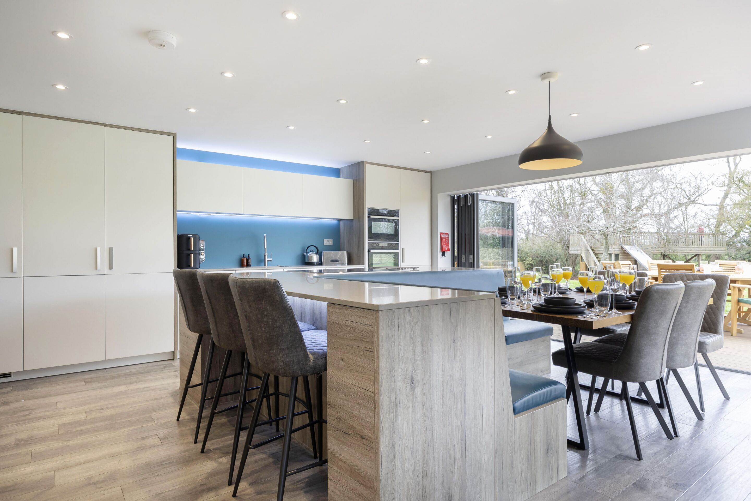 Une cuisine moderne dotée d’un îlot central, de tabourets de bar et d’un coin repas avec des chaises.