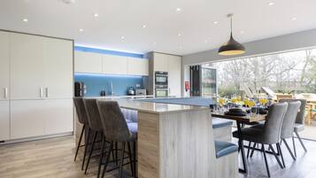 A modern kitchen with a central island, bar stools, and a dining area with chairs.