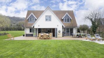A house with a large patio, a dining area, and two lounge chairs.