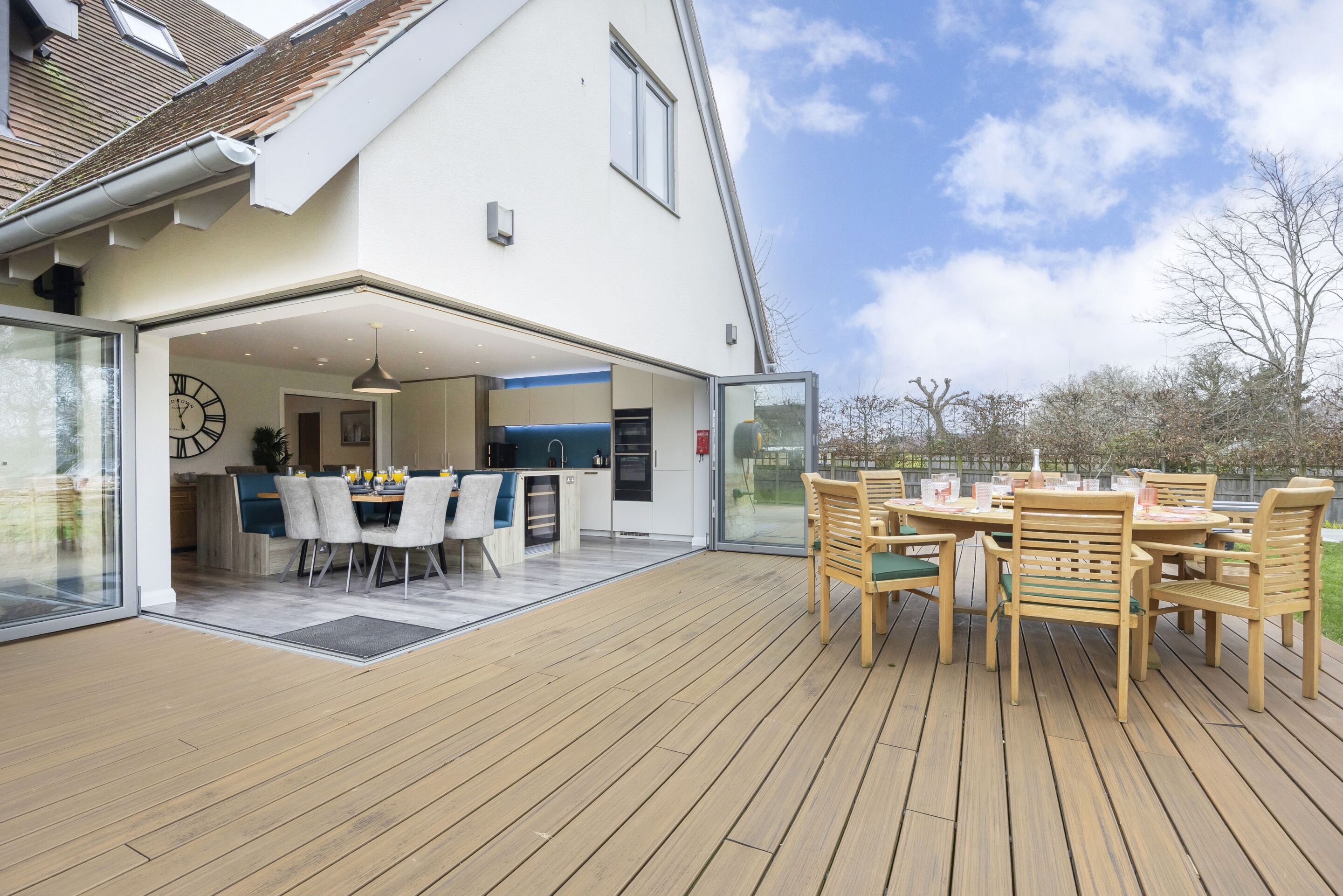 An open-plan living area with a dining table and chairs, a kitchen, and a large glass door leading to a deck.