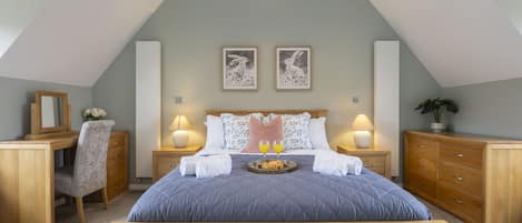 Ein Schlafzimmer mit Bett, Nachttischen, Schreibtisch, Stuhl und zwei gerahmten Bildern an der Wand.