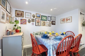 A dining area with a table set for four, surrounded by red chairs, with framed artwork on the walls.