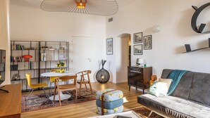 A modern living room with a dining area, a sofa, a coffee table, and a bookshelf. - Casa Bianca – Charme & vue mer au cœur d’Erbalunga (Brando)