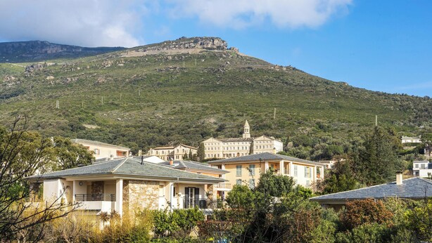 A coastal town with buildings, a hill with a tower, and a clear sky. - Casa Bianca – Charme & vue mer au cœur d’Erbalunga (Brando)