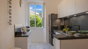 A modern kitchen with a window, a refrigerator, a sink, and a countertop with kitchenware. - Casa Bianca – Charme & vue mer au cœur d’Erbalunga (Brando)