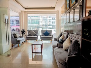 Una sala de estar moderna con un sofá, dos sillones, una mesita de centro y un ventanal con vistas a la ciudad.