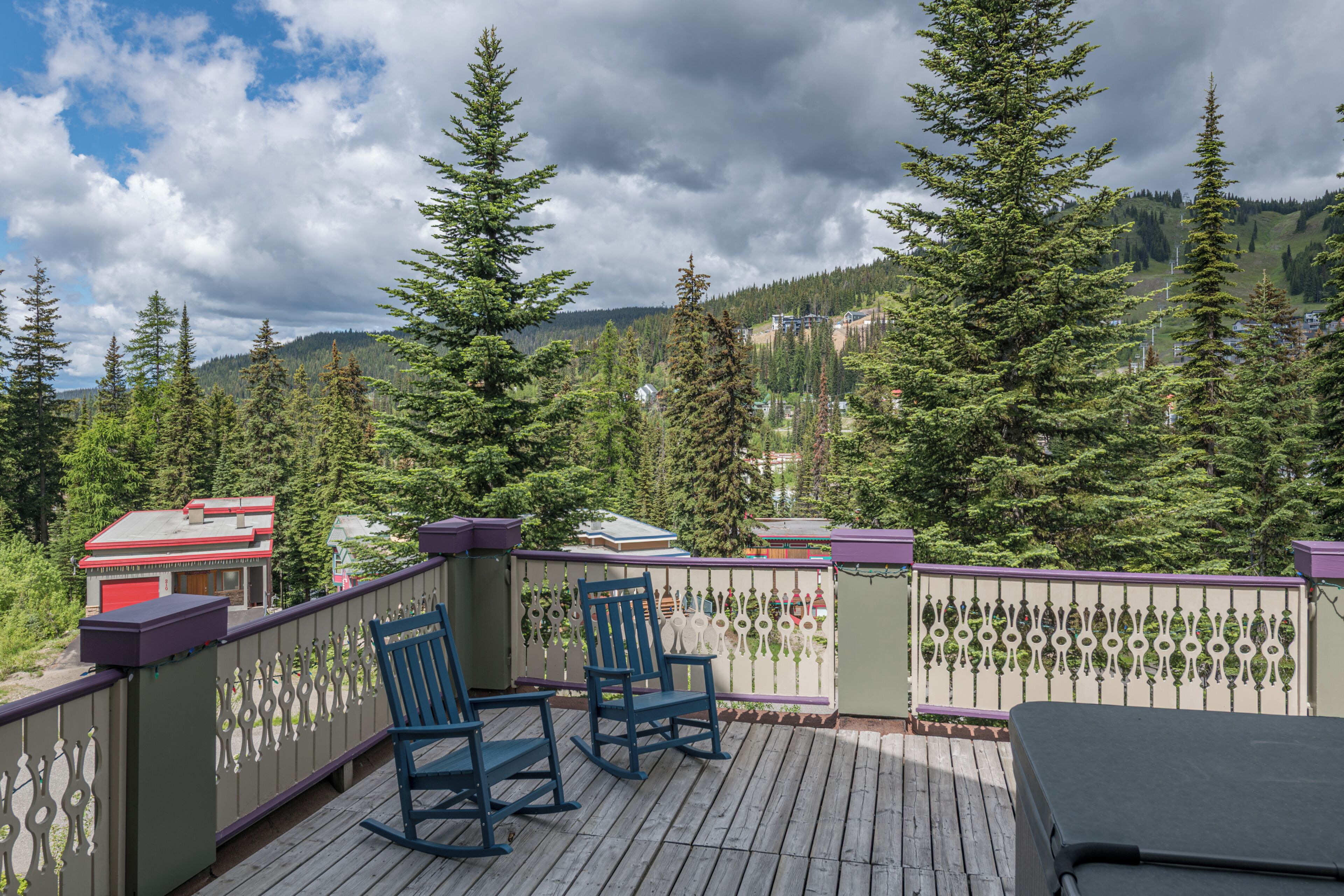 A deck with two rocking chairs and a view of a forested mountain area.