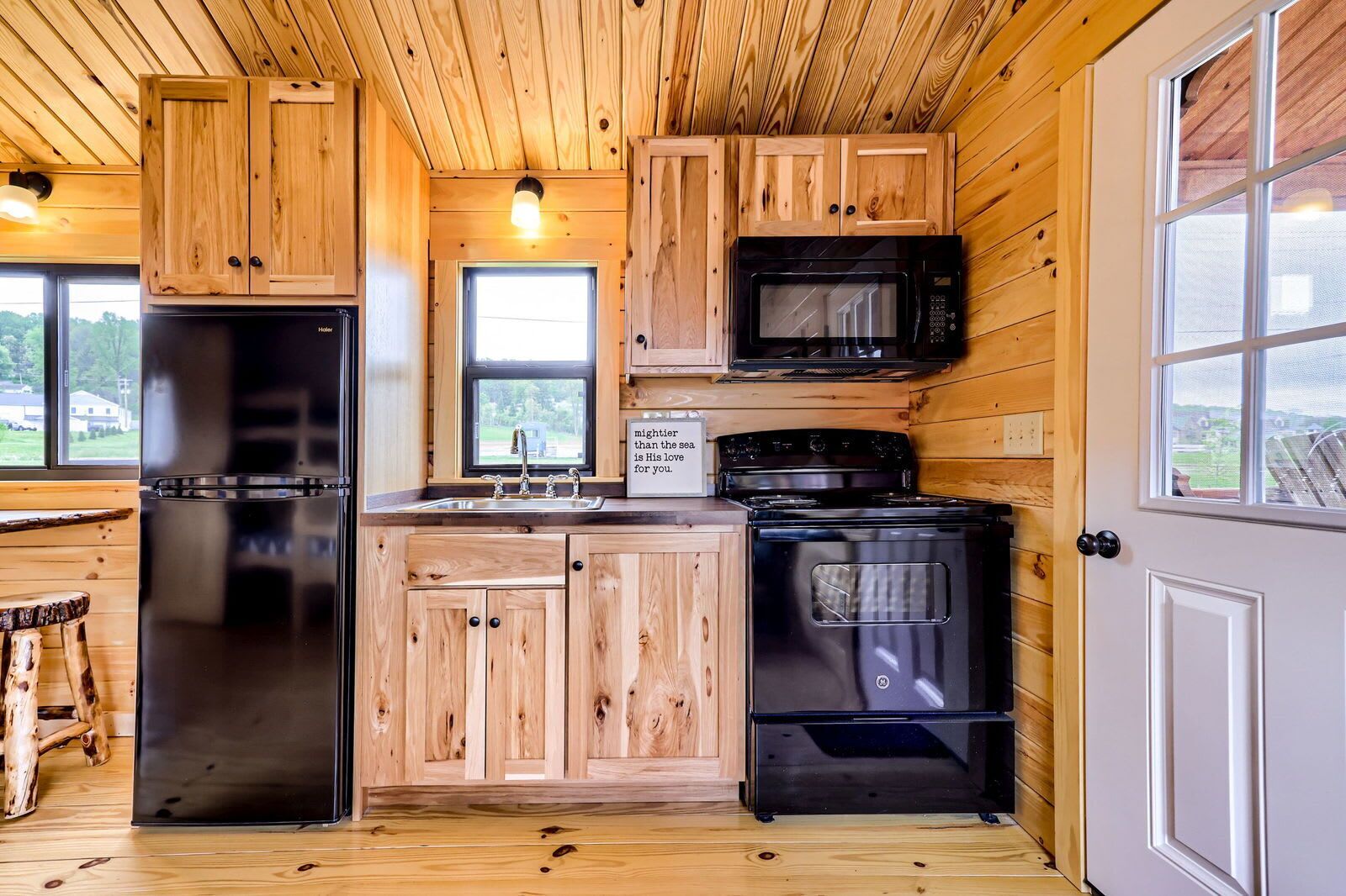 Une cuisine avec des meubles de rangement en bois, un réfrigérateur, un four à micro-ondes, un four et un évier.