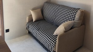 Una sala de estar moderna con un sofá a cuadros, un televisor de pantalla plana montado en la pared y un piso de color claro.