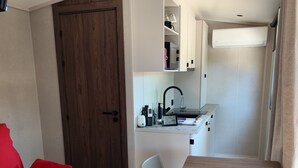 Un espacio habitable compacto con kitchenette, zona de comedor y sofá rojo.