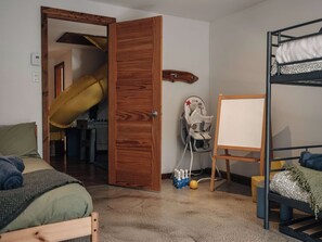 A room with a bunk bed, a wooden door, a whiteboard, and a yellow slide. - Bali-Zen | Spa & lake front with boats (Saint-Côme)
