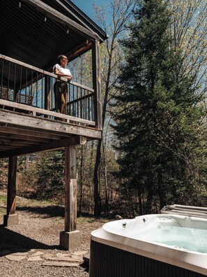 Una terraza de madera con un jacuzzi y una persona de pie allí.