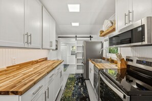 A modern kitchen with white cabinetry, stainless steel appliances, and a wooden countertop. - Cedar Key Hayes David Cottage (Cedar Key)