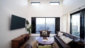 A modern living room with a large flat-screen TV, leather sofas, a coffee table, and a large window with blinds. - Solana Apartments  (Nadi)
