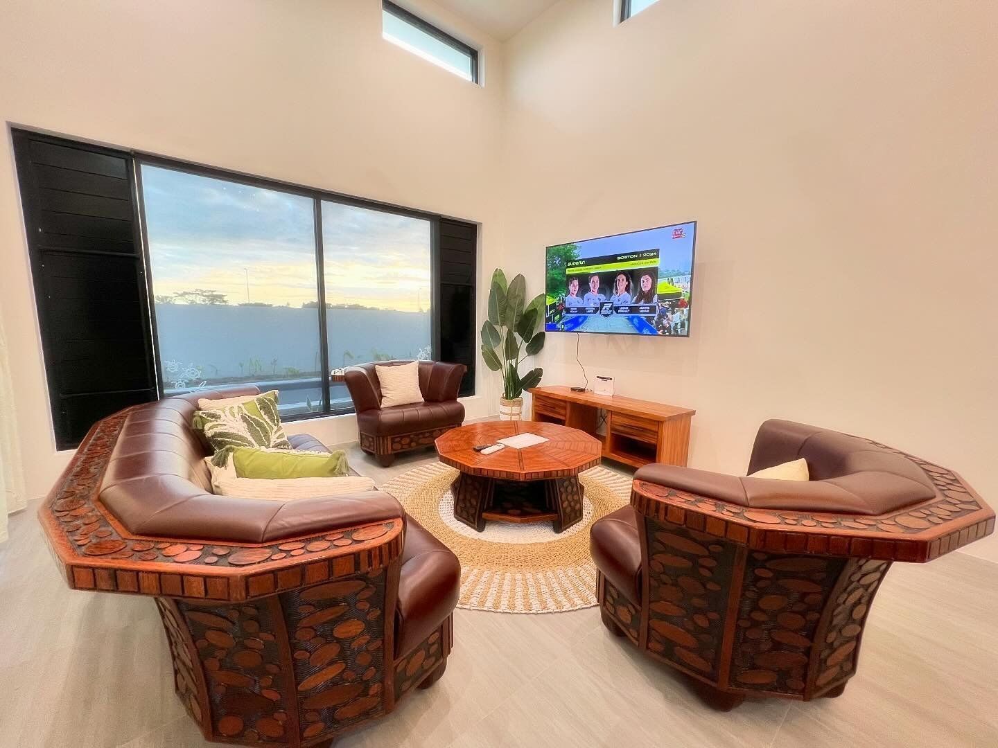 A modern living room with a large window, a round coffee table, and leather sofas.