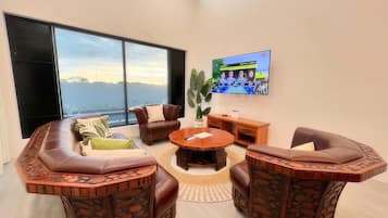 A modern living room with a large window, a round coffee table, and leather sofas.