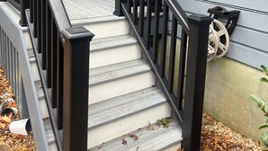 Una escalera con barandillas negras que lleva a un porche.