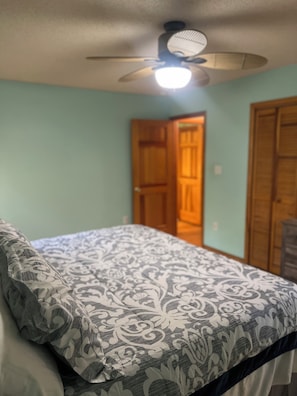 A bedroom with a bed, a ceiling fan, and a door. - Family-friendly, Spacious, One-Level 4-Bedroom Home in Tranquil Southern Shores (Kitty Hawk)