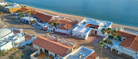A coastal residential area with buildings, a beach, and a clear view of the sea.