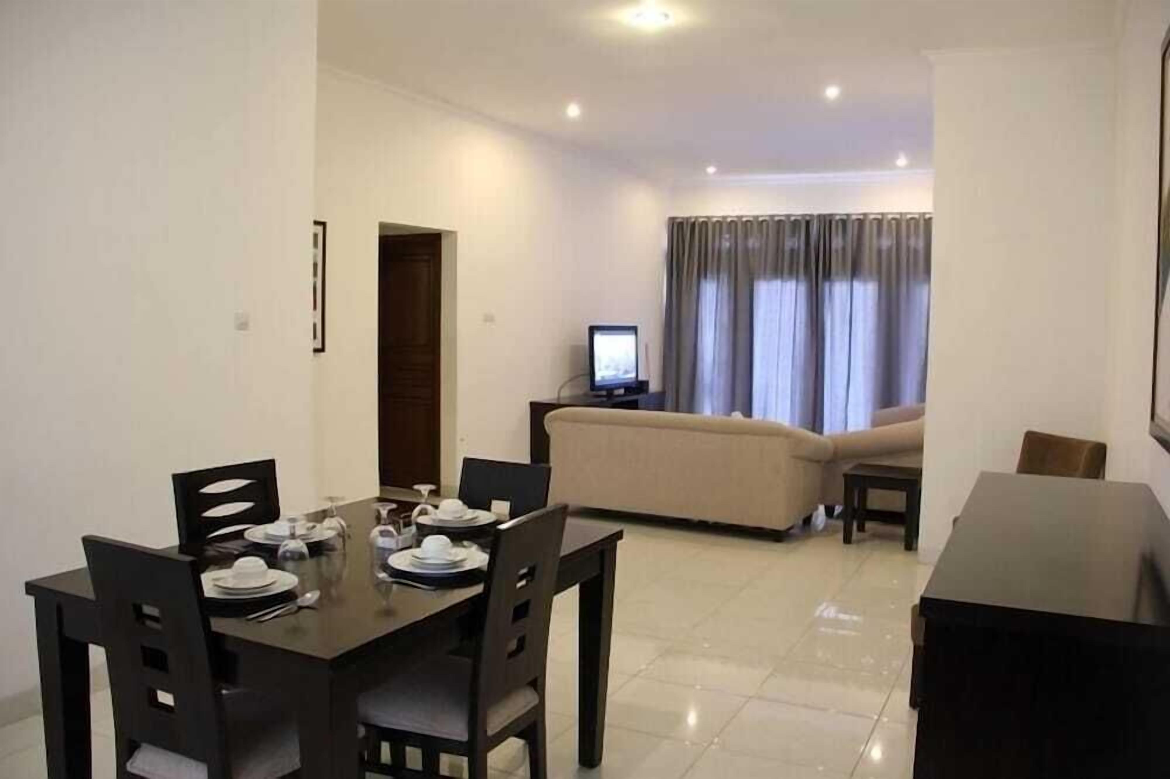 A dining area with a table set for four, a sofa, a TV, and a small table in a living room.