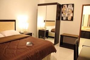 Une chambre d’hôtel avec un lit, des tables de chevet, un miroir et des œuvres d’art accrochées au mur.