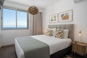 Een moderne slaapkamer met een groot bed, een nachtkastje, een lamp en twee ingelijste kunstwerken aan de muur.