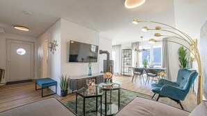 Ein modernes Wohnzimmer mit einer Couch, einem Glastisch, einem Fernseher und einem Essbereich mit Stühlen und Tisch.