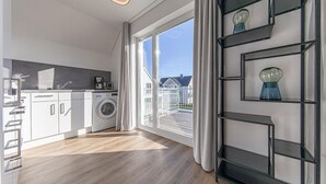Eine moderne Küche mit Waschmaschine, Kaffeemaschine und Blick auf eine Wohngegend.