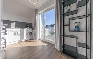 Eine moderne Küche mit Waschmaschine, Kaffeemaschine und Blick auf eine Wohngegend.