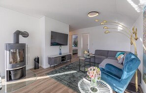 A modern living room with a fireplace, a flat-screen TV, a sofa, and a decorative lamp. - Awesome apartment in OstseeResort Olpenitz (OstseeResort Olpenitz)