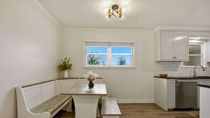 Una cocina con armarios blancos, un banco de madera, una ventana y una lámpara en el techo.
