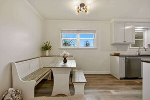A kitchen with white cabinetry, a wooden bench, a window, and a ceiling light fixture. - Dog’s Perfect Vacation｜54 Acres｜18 min Spring Hill (Columbia)