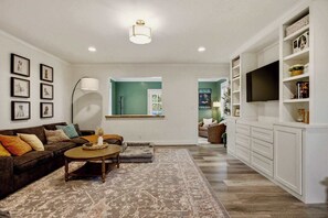 A living room with a sofa, coffee table, and a TV on a white cabinet. - Dog’s Perfect Vacation｜54 Acres｜18 min Spring Hill (Columbia)