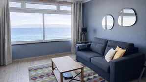 Un salon moderne avec un canapé, une petite table, une lampe et une vue sur la mer.