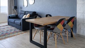 Un salon moderne avec un canapé foncé, une table à manger en bois et des chaises à motifs.